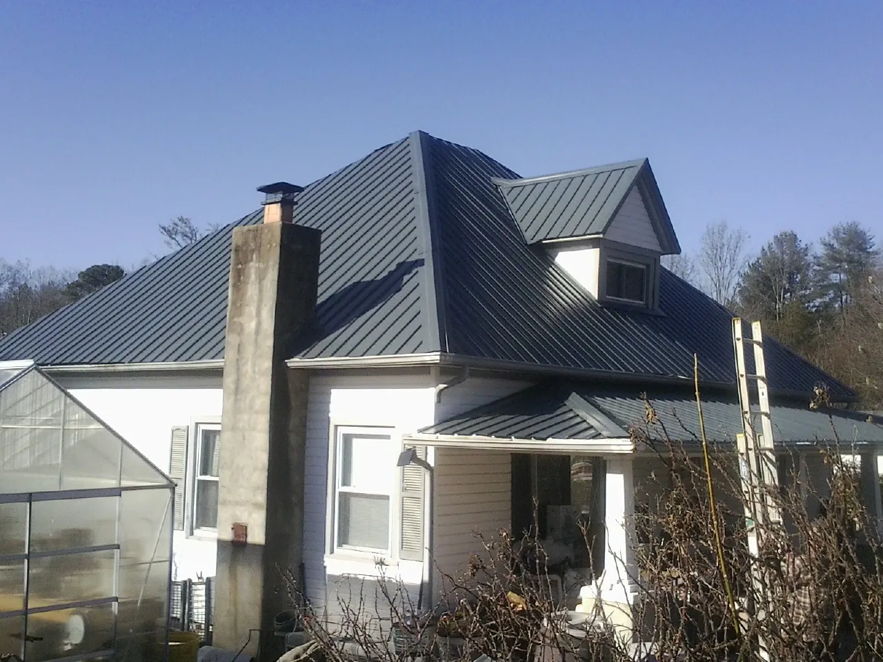 Dark blue standing seam metal roof on a white farmhouse with dormer — Slate & Tile Roof Repair by Roofing Brothers in Lane City