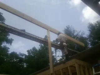 Carpenter setting a ridge beam over a new addition frame — Ice Dam Removal by Roofing Brothers in Lane City