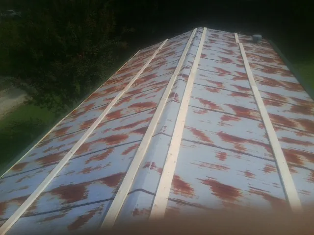 Rusted metal roof panels with new wood purlins before replacement — Storm Damage Roof Repair in Lane City by Roofing Brothers