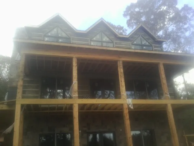 Dormers and porch framing on a large log home under construction — Roof Coating work by our crew in Lane City