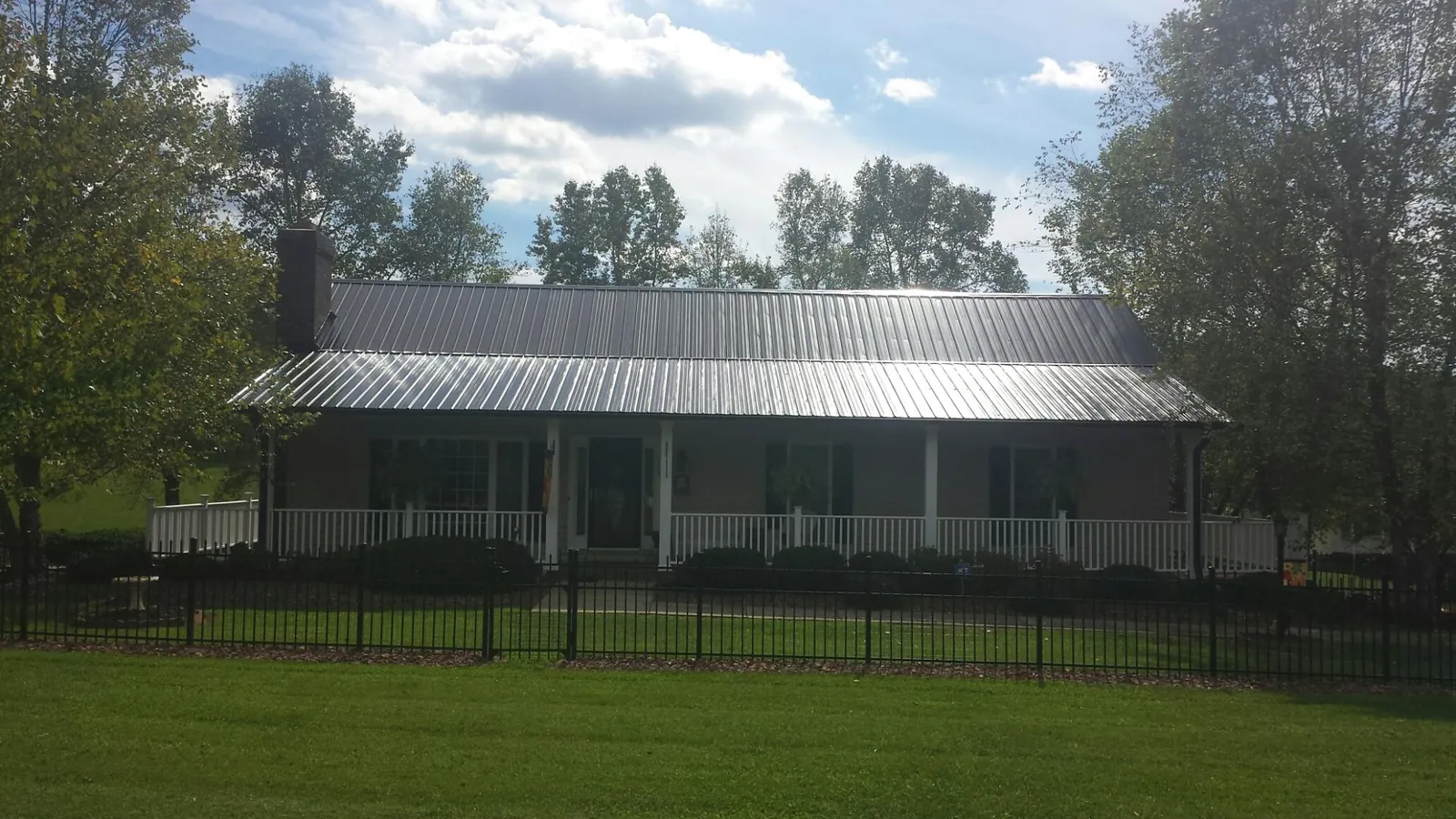 Gray metal roof on a brick ranch with a full width front porch — Gutter Guard Installation work by our crew in Lane City