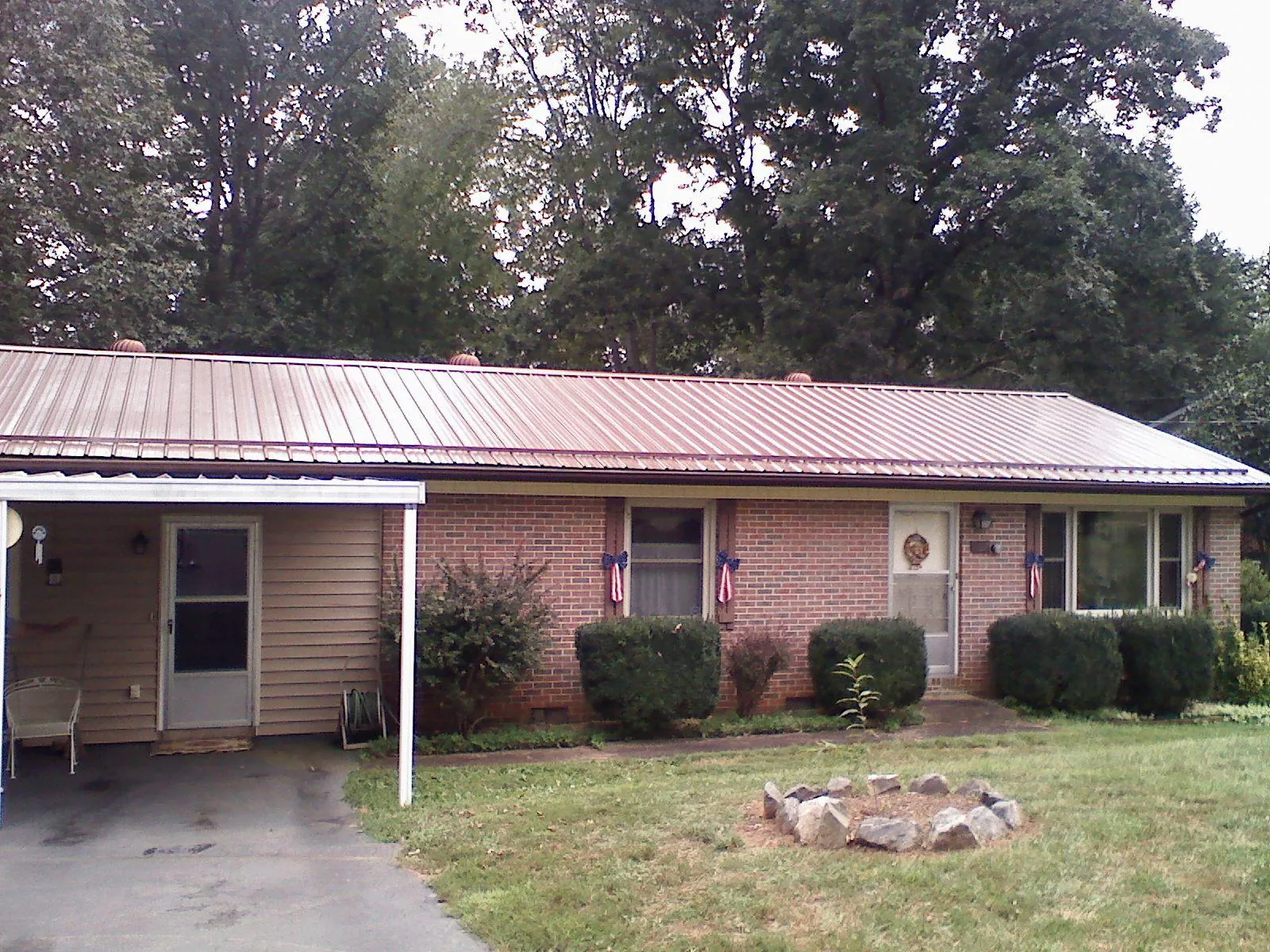 Bronze metal roof and carport on a brick ranch home — Roof Repair work by our crew in Lane City