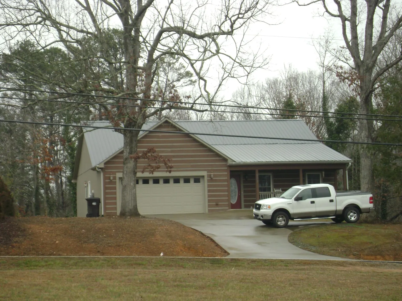 Gray metal roof on a log sided house with an attached two car garage in Lane City