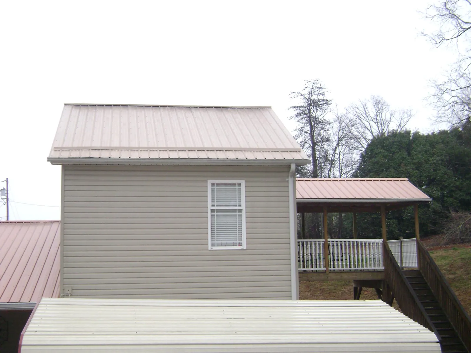 Tan metal roofs on a two story addition and attached porch, from a Roof Replacement job in Lane City