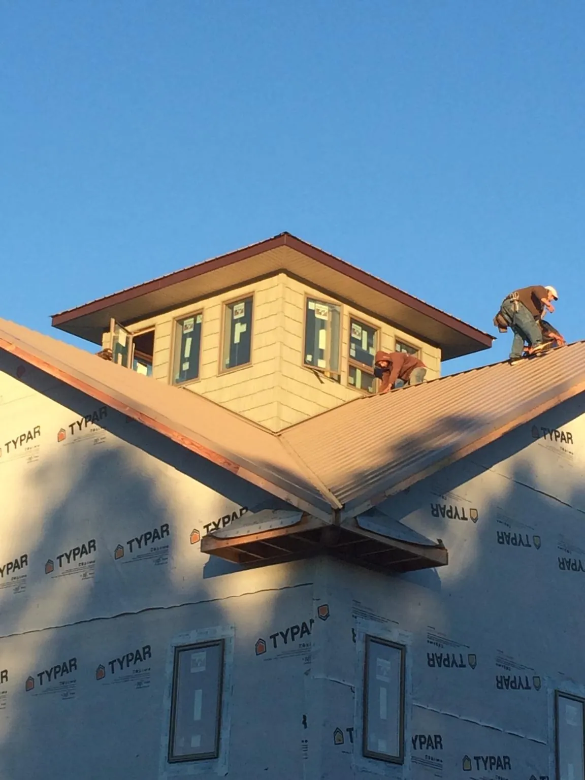 Roofers working around a rooftop cupola on a new metal roof at sunset — Roof Waterproofing in Lane City by Roofing Brothers